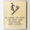 Eco-friendly ADA braille wood sign using 3D printing that says “In case of fire do not use elevator, use stairs"