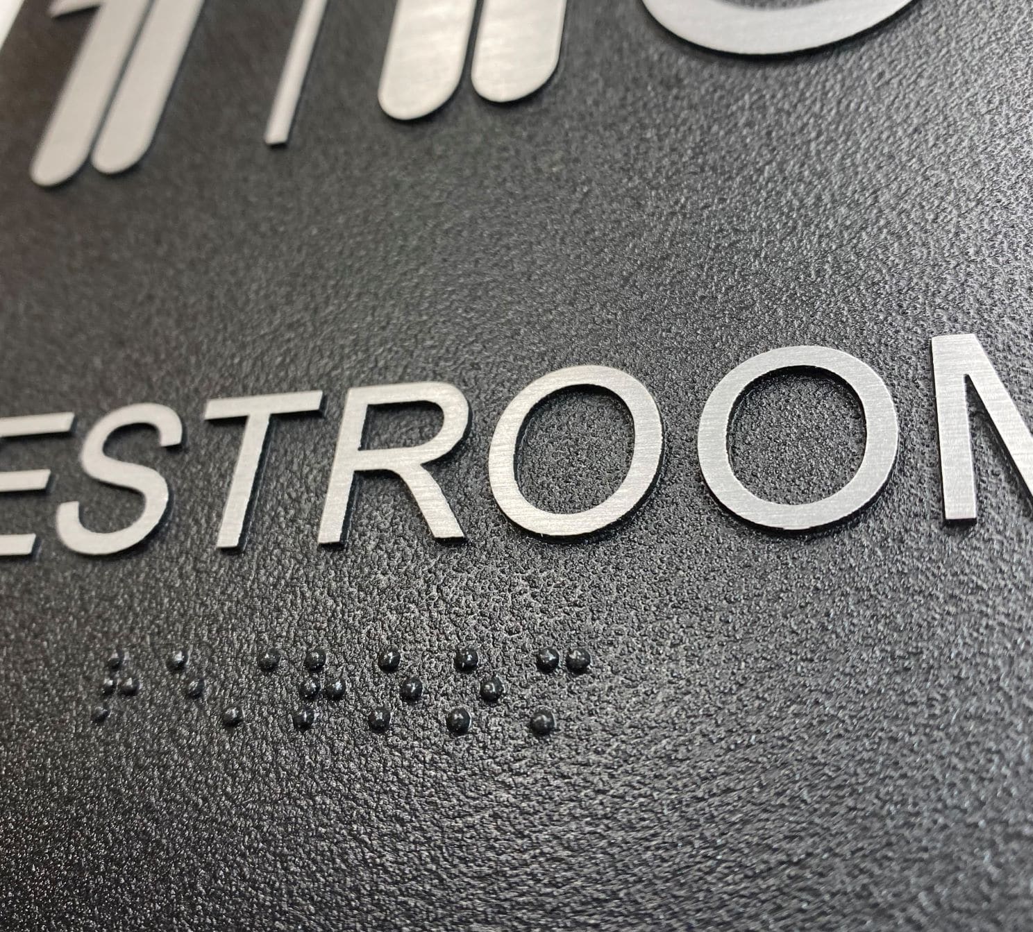 braille close up of exterior ADA all gender restroom sign